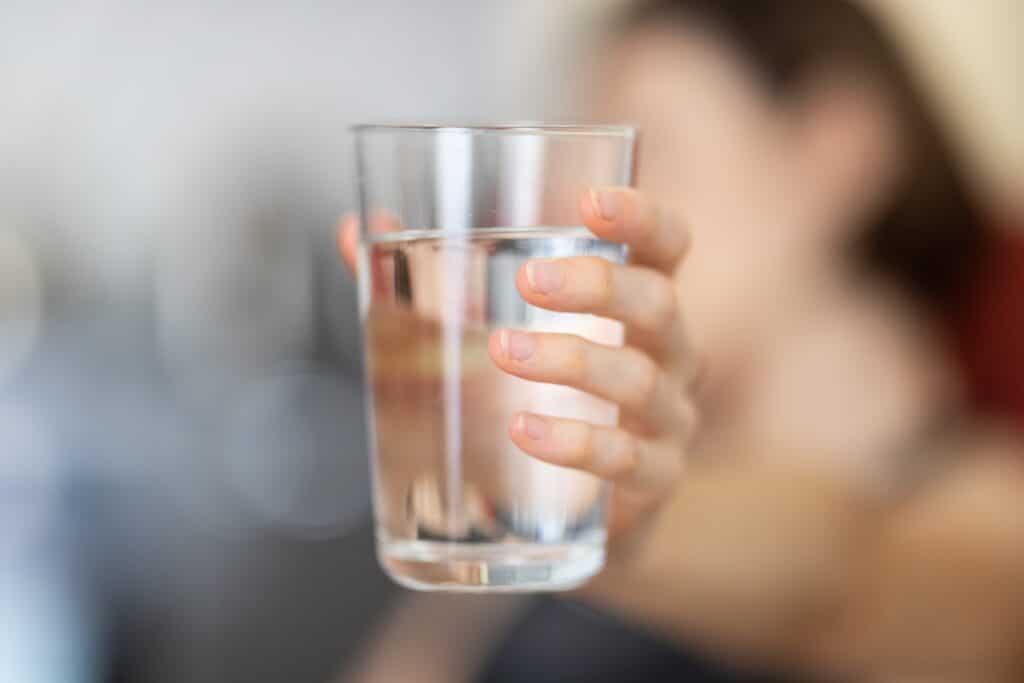 femme tenant un grand verre d'eau, boisson essentielle à un repas équilibré