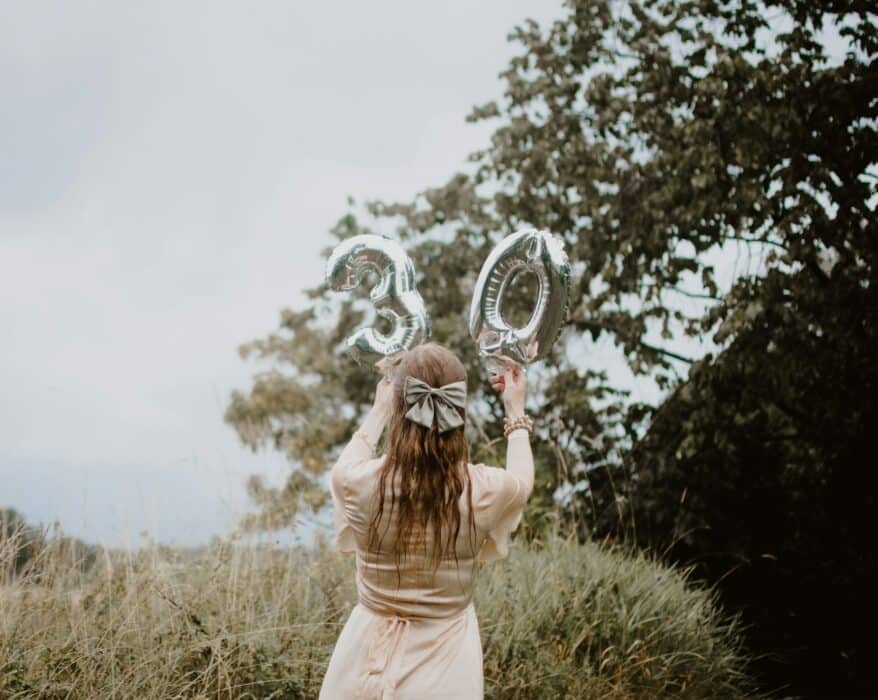Femme tenant des ballons ayant la forme d'un 3 et d'un 0 pour ses 30 ans